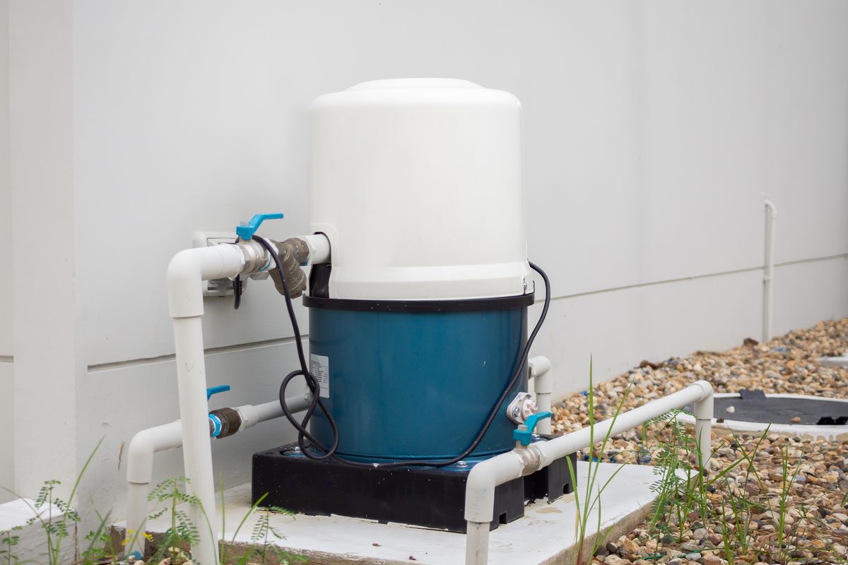 Pressure tank and pump set on a concrete pad outside a house